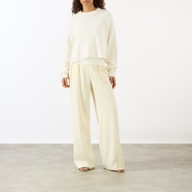 Model wearing Lisa Yang The Karine Sweater in cream cashmere with crew neck, styled with matching wide-leg cream trousers and sandals.