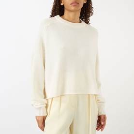 Model wearing Lisa Yang The Karine Sweater in cream cashmere with crew neck, dropped shoulders and ribbed trims, styled with cream trousers