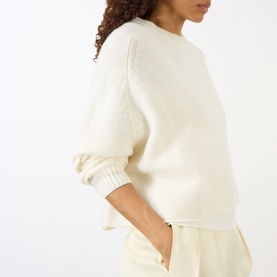 Model wearing Lisa Yang The Karine Sweater in cream cashmere, crew neck with dropped shoulders and ribbed trims, styled with cream trousers.