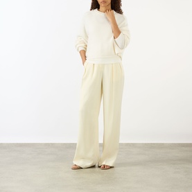 Model wearing Lisa Yang The Karine Sweater in cream cashmere with crew neck and dropped shoulders, styled with wide-leg cream trousers.