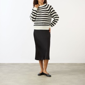 Model wearing Lisa Yang cream and black striped cashmere-silk jumper, styled with black midi skirt and black flat shoes.