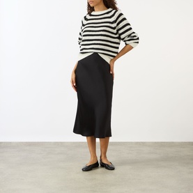 Model wearing Lisa Yang cream and black stripe cashmere silk knit top, styled with black midi skirt and black ballet flats.