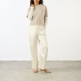 Model wearing Lisa Yang Sand cashmere top with cream wide-leg trousers and nude strappy heeled mules.