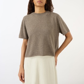 Model wearing Lisa Yang cashmere T-shirt in Truffle, short sleeves, crew neck, styled with a white skirt.