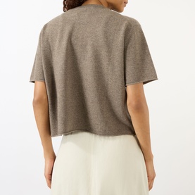 Model wearing Lisa Yang cashmere T-shirt in Truffle, back view, cropped fit with short sleeves, styled with cream wide-leg trousers.
