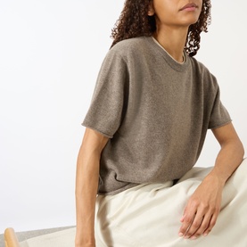 Model wearing Lisa Yang cashmere T-shirt in Truffle, V-neck, short sleeves, styled with cream wide-leg trousers.