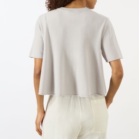 Model wearing Lisa Yang Liru Cashmere T-Shirt in Seashell, back view, cropped cut, round neck, short sleeves, styled with cream trousers