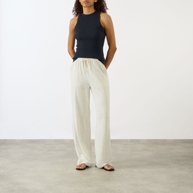 Model wearing Lisa Yang Amya Rib Tank Top in Navy, sleeveless ribbed cotton-cashmere, styled with cream wide-leg trousers and brown sandals.