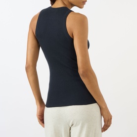 Model wearing Lisa Yang Amya Rib Tank Top in navy, ribbed sleeveless style with round neck, shown from back, styled with grey trousers.