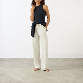 Model wearing Lisa Yang Amya Rib Tank Top in Navy, sleeveless ribbed style, paired with cream wide-leg trousers and tan sandals.