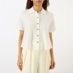 Model wearing Lisa Yang cream cashmere short-sleeve button-through top with collar, styled with wide-leg cream trousers