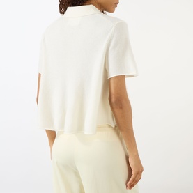 Model wearing Lisa Yang cream cashmere top, back view, short sleeves, cropped length, styled with matching cream trousers