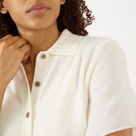 Model wearing Lisa Yang cream cashmere top with short sleeves, collared neckline and tortoiseshell buttons, close-up detail view.