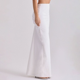 Model wearing House of CB white maxi skirt with ruched waist detail, floor-length flared silhouette, styled with strappy heels