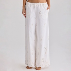 Model wearing House of CB white wide-leg trousers with floral embroidery, elasticated waistband and side pockets