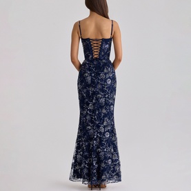 Model wearing navy blue floral embroidered maxi dress with lace-up corset back, spaghetti straps, and fishtail hem