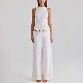Model wearing House of CB white embroidered peplum top and wide-leg trousers set with floral cutwork detailing