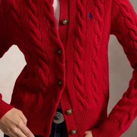 Model wearing Polo Ralph Lauren red cable-knit cardigan with gold buttons and embroidered pony logo, styled with a belted trouser.