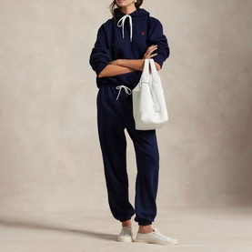 Model wearing Polo Ralph Lauren Cruise Navy hoodie with matching joggers, carrying a white tote bag, styled with white trainers.