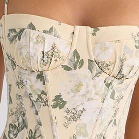 Model wearing House of CB taupe floral corset top with sweetheart neckline, boning detail, and white and green botanical print.