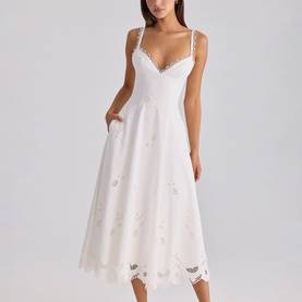 Model wearing House of CB white midi dress with V-neckline, lace trim hem, floral embroidery, and thin straps