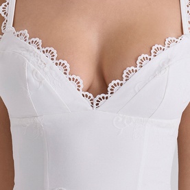 Model wearing House of CB white bustier top with scalloped lace trim neckline, close-up detail view