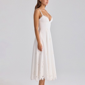Model wearing House of CB white midi dress with spaghetti straps, V-neckline, and floral lace hem, side view