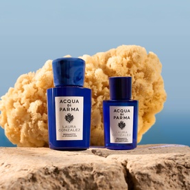 Acqua Di Parma Blu Mediterraneo two blue glass fragrance bottles displayed on stone with natural sponge against blue background