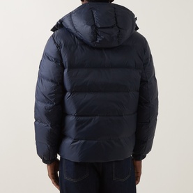 Model wearing Calvin Klein Jeans Dark Sapphire puffer jacket, rear view showing hooded design, quilted panels, paired with dark jeans.