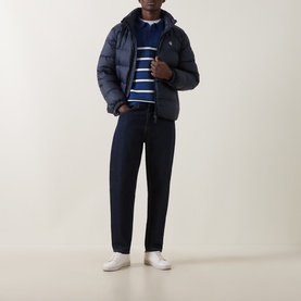 Model wearing Calvin Klein Jeans Dark Sapphire puffer jacket, styled with navy stripe knit, dark jeans and white trainers.