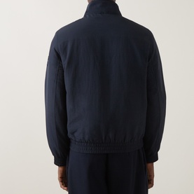 Model wearing Calvin Klein Jeans Dark Sapphire nylon casual jacket, back view, with matching trousers.