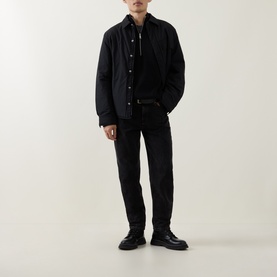Model wearing Calvin Klein Jeans Back Graphic Padded Overshirt in black, styled with black jeans, belt and lace-up boots.
