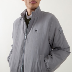 Model wearing Calvin Klein Jeans Harrington Logo Weatherproof Jacket in Convoy grey, padded with stand collar and monogram logo embroidery.