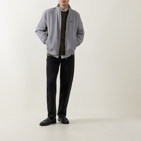 Model wearing Calvin Klein Jeans Harrington Logo Weatherproof Jacket in Convoy grey, styled with black trousers and dark leather shoes.