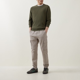 Model wearing Calvin Klein Jeans Comfort Skinny Leg Cargo Trousers in Vintage Khaki with cuffed ankles, styled with an olive knit sweater.