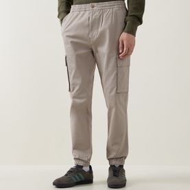 Model wearing Calvin Klein Jeans Comfort Skinny Leg Cargo Trousers in Vintage Khaki with cuffed ankles and side cargo pockets, styled with green