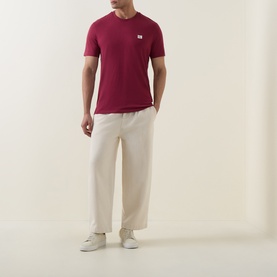 Model wearing Calvin Klein Jeans Rhododendron crew neck T-shirt with cream wide-leg trousers and white trainers.