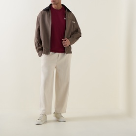 Model wearing Calvin Klein Jeans Rhododendron Crew Neck T, styled with taupe zip jacket, cream trousers and white trainers.