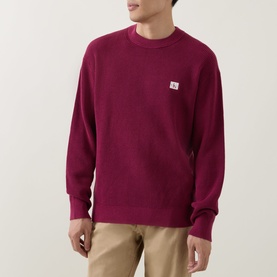 Model wearing Calvin Klein Jeans Badge Logo Waffle-Knit Sweatshirt in Rhododendron, crew neck with chest badge logo, styled with beige chinos