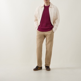 Model wearing Calvin Klein Jeans Badge Logo Waffle-Knit Sweatshirt in Rhododendron, styled with ecru jacket, beige chinos and dark trainers.