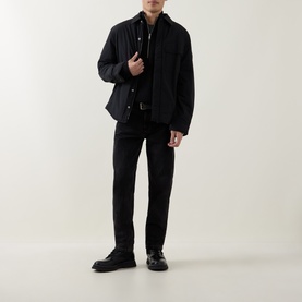 Model wearing Calvin Klein Jeans Badge Logo Waffle-Knit Half-Zip Sweatshirt in black, styled with black jacket, trousers, and loafers