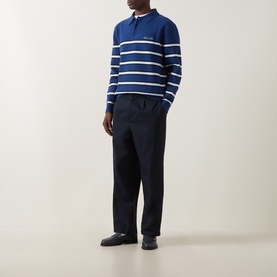 Model wearing a navy and white striped knit polo sweater, styled with navy trousers and dark loafers