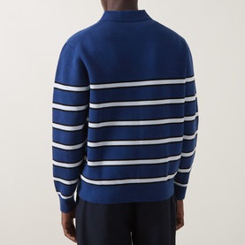 Model wearing blue and white striped knit sweater with mock neck, long sleeves, and ribbed cuffs, styled with navy trousers