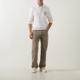 Model wearing Calvin Klein Jeans Tofu cotton sweatshirt with logo, styled with taupe trousers and white trainers.