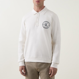 Model wearing Calvin Klein Jeans Tofu sweatshirt with polo collar, long sleeves, and circular logo graphic on chest, styled with beige trousers