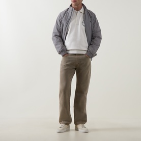 Model wearing Calvin Klein Jeans Tofu sweatshirt, styled with grey padded jacket, taupe trousers and white trainers.