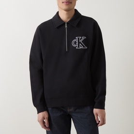 Model wearing black Calvin Klein half-zip sweatshirt with embroidered CK logo, polo collar, styled with dark jeans