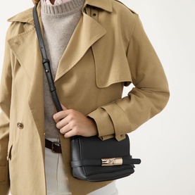 Model carrying Longchamp Le Smart Crossbody Bag in black pebbled leather with gold-toned hardware and adjustable strap, styled with a beige trench