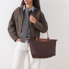 Model carrying Longchamp Le Pliage Original Large Tote Bag in Moka, with brown leather trims, gold-tone hardware and short top handles