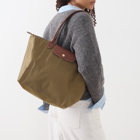 Model carrying Longchamp Le Pliage Original Large Tote Bag in olive, brown leather trims, gold-tone hardware, dual top handles, styled with grey knit